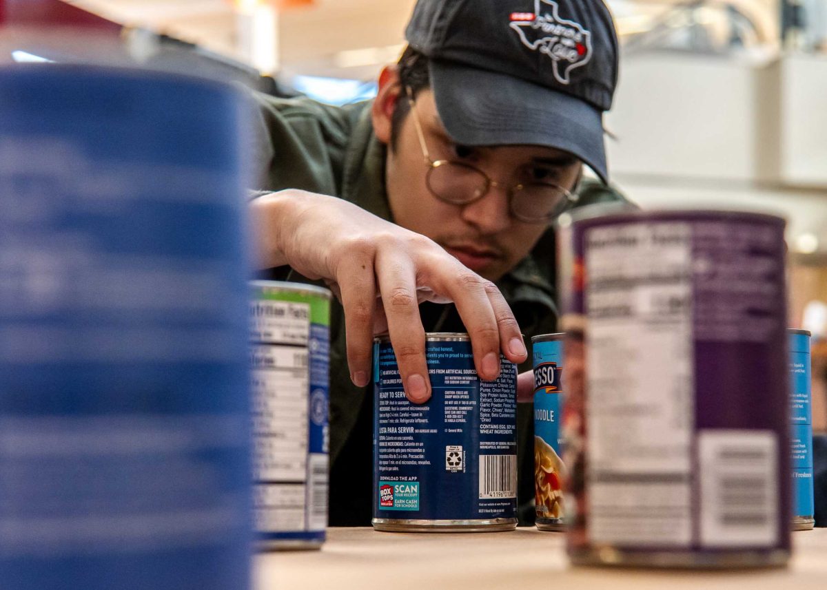 Sophomore Architecture Major Hiram De Los Reyes carefully places cans of soup while competing at Canstruction Build Day for SAC's AIA Chapter at North Star Mall at Sept. 8. Photo by A. De Leon.