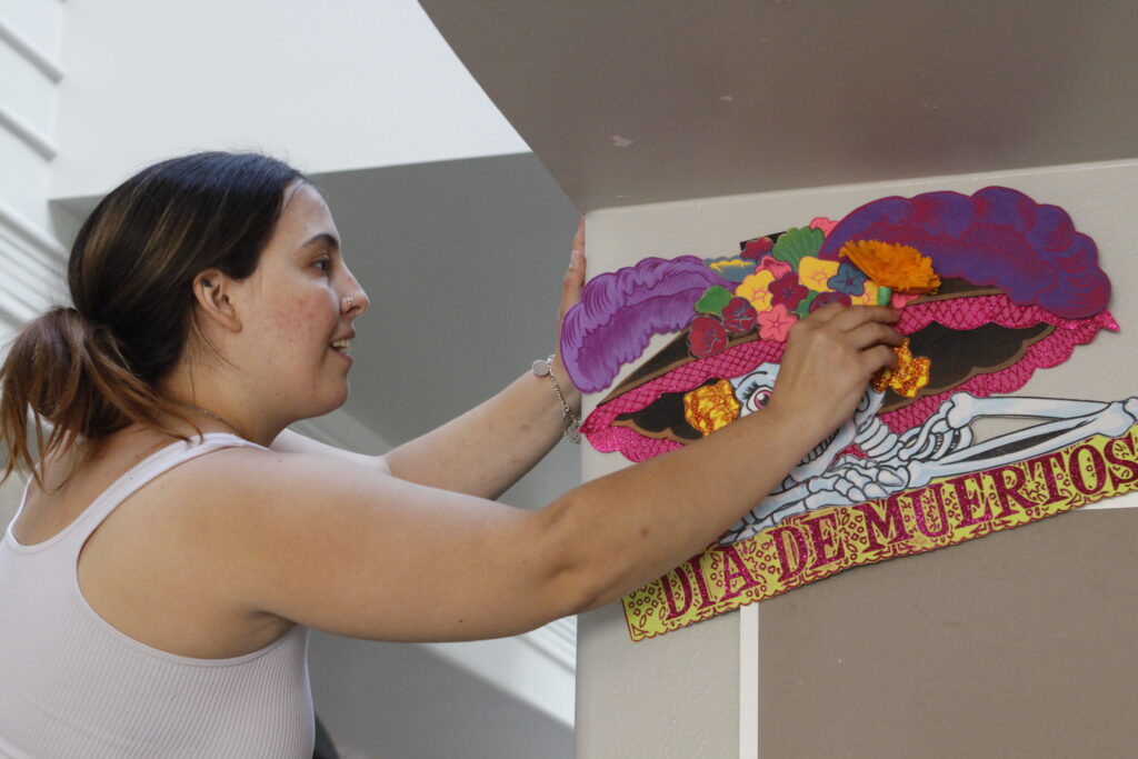 Mia Guidry, a sophomore mechanical-engineering student, helps build SAC’s Dia De Los Muertos ofrenda in the Loftin Student Center atrium Oct. 9. Photo by Natalia Edwards.