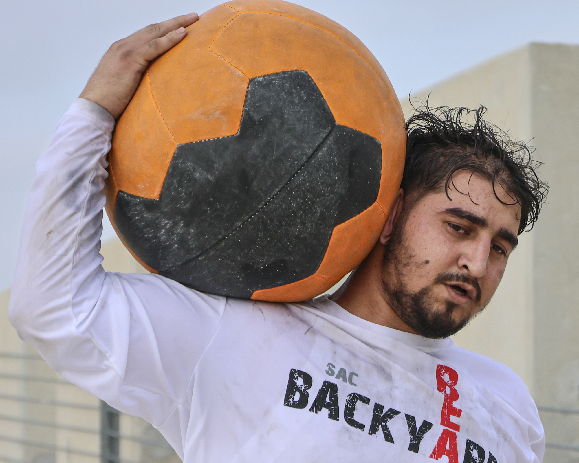 A competitor runs with a medicine ball after completing the “Reverse Cannonball” portion of the Backyard Beast Team Lana Patterson.