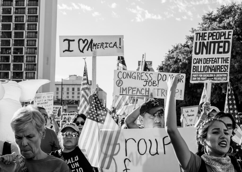 A group of protesters chant and march while holding signs and flags at the “No Kings” protest Saturday. Photo by Jacob R. Lopez.