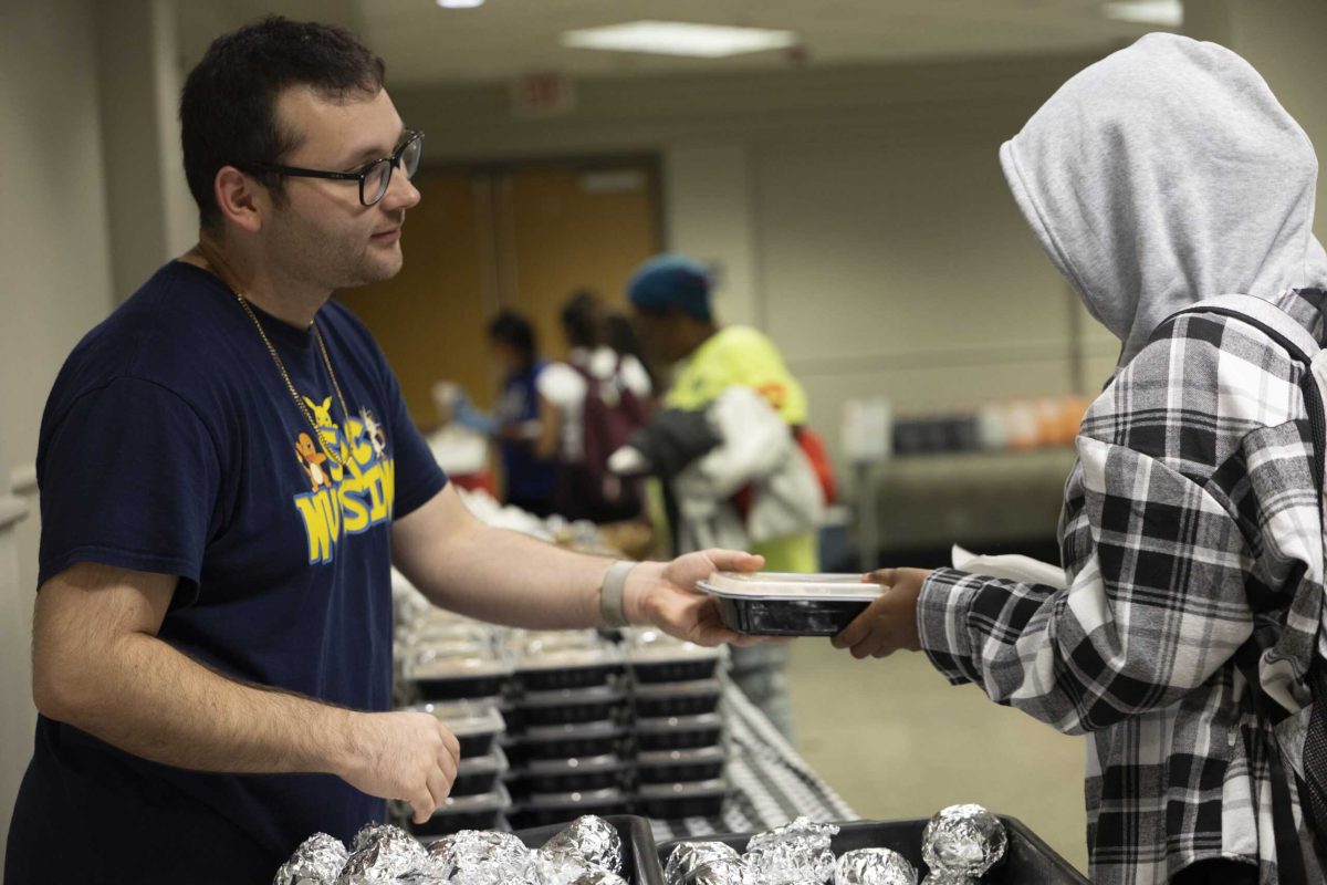 Nursing major Eli Gallegos hands out plates of food at the Thanksgiving Student Luncheon Nov. 19. Photo by Catie Broadus.