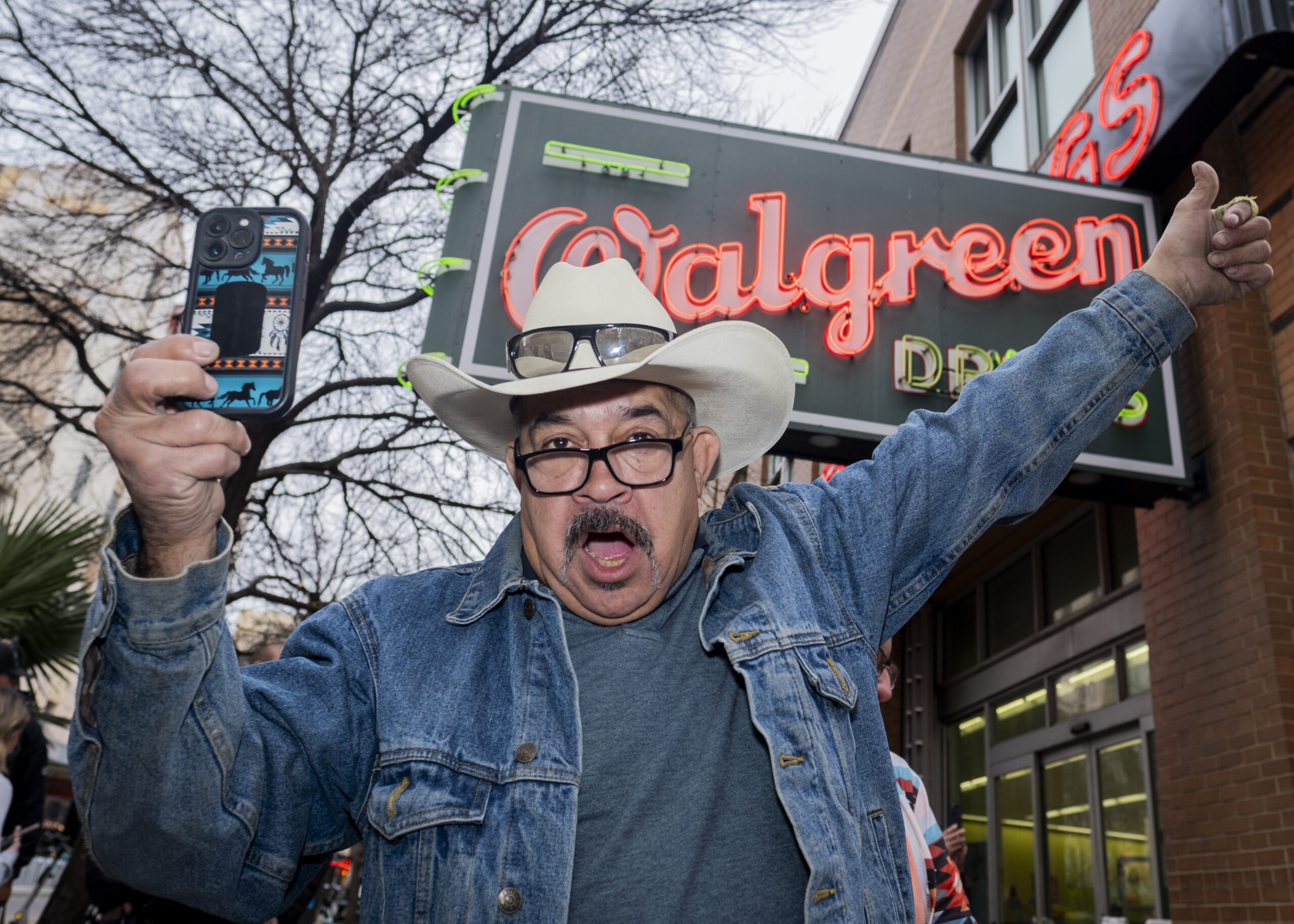 A protester gives a thumbs up as he records the crowd from the corner of E Houston and Navarro Friday. Photo by Jacob R. Lopez.