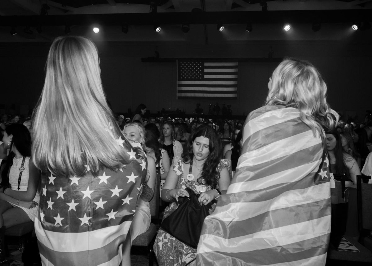 Two attendees of Turning Point USA's Women's Leadership Summit look towards the crowd as they dance to Christian dance music on June 5.