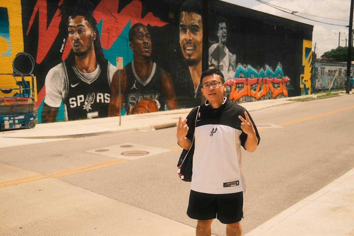 Taro Kotani poses in front of the Guadalupe St. Spurs mural at 125 Guadalupe St. (Photo courtesy of Taro Kotani)